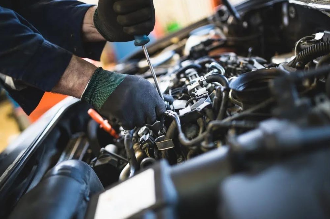 a mechanic tightening a bolt in a car hood